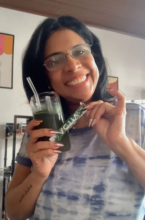 Clienta sonriendo con su vaso de Activ Greens y un sobre